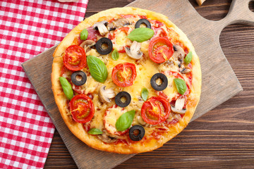 Tasty pizza with vegetables and basil on table close up