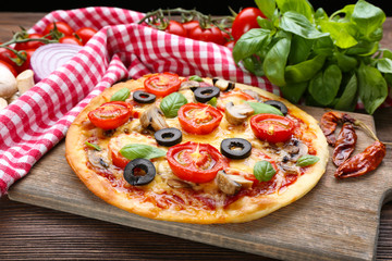 Tasty pizza with vegetables and basil on table close up