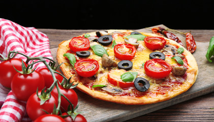 Tasty pizza with vegetables and basil on black background