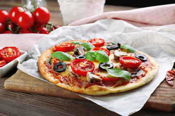 Tasty pizza with vegetables and basil on table close up