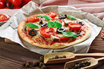 Tasty pizza with vegetables and basil on table close up