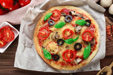 Tasty pizza with vegetables and basil on table close up