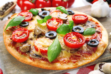 Tasty pizza with vegetables and basil on table close up