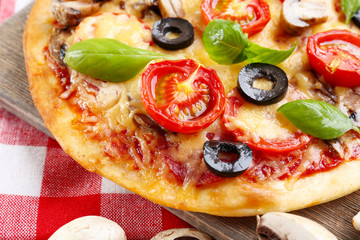 Tasty pizza with vegetables and basil on table close up