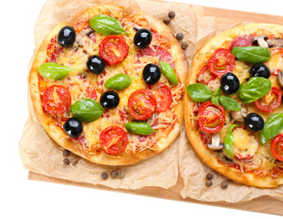 Tasty pizza with vegetables and basil on cutting board isolated on white