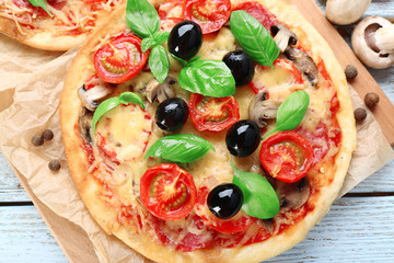 Tasty pizza with vegetables and basil on table close up