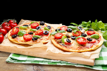 Tasty pizza with vegetables and basil on black background