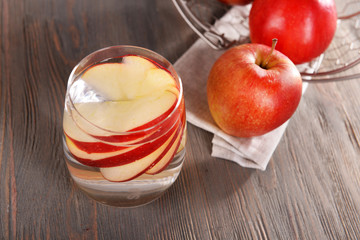 Glass of apple cider with fruits on wooden background