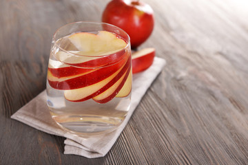 Glass of apple cider with fruits on wooden background