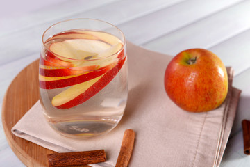 Glass of apple cider with fruits and cinnamon on table close up