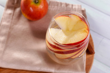 Glass of apple cider with fruits and cinnamon on table close up