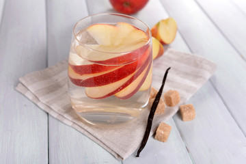 Glass of apple cider with fruits and vanilla stick on table close up