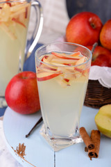 Glass and carafe of apple cider with fruits and spices on table close up