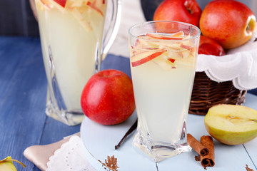 Glass and carafe of apple cider with fruits and spices on table close up