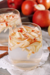 Glasses of apple cider with fruits and cinnamon on table close up