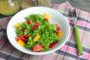 Bowl of fresh green salad on table with napkin, closeup