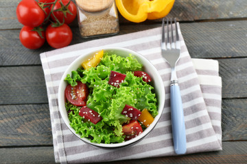 Bowl of fresh green salad on wooden table, top view