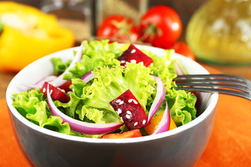 Bowl of fresh green salad on table with napkin, closeup