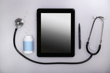 Medical tablet with stethoscope on white background