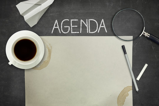 Agenda concept on black blackboard with empty paper sheet