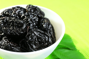Saucer of prunes with leaves on green napkin, closeup
