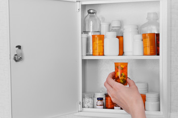 Female hand taking pills from medicine chest, closeup