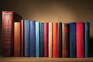 Old books on shelf, close-up, on dark wooden background