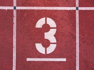 Number three. White track number on red rubber racetrack, texture of running racetracks in athletic...