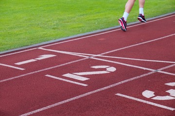 Fototapeta premium Red running racetrack on the stadium with two running legs