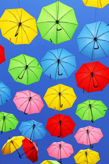 Fototapeta na wymiar Colors / Colorful umbrellas floating magically in the sunny blue sky