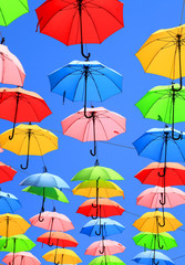 Fototapeta na wymiar Colors / Colorful umbrellas floating magically in the sunny blue sky