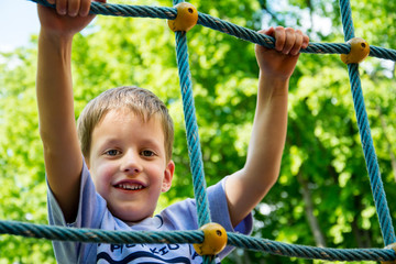 Young boy climbing rope on kid playground