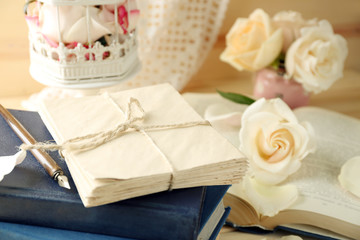 Fresh roses with old book, key and letters on wooden table background. Vintage concept