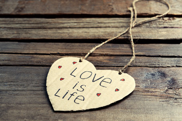 Written message on cardboard heart on wooden background