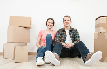 Happy young man and woman sitting near  cardboard boxes