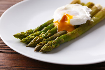 Roasted asparagus with poached egg on plate on table close up