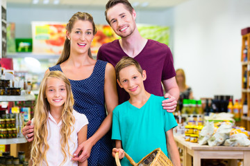 Eltern und Kinder wählen Gemüse in einer Bio Supermarkt Frischeabteilung