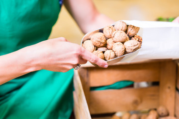 Biomarkt Angestellter füllt Walnüsse in Tüten der Frischeabteilung auf