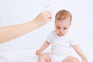 Fototapeta premium Mother is combing beautiful baby`s hair