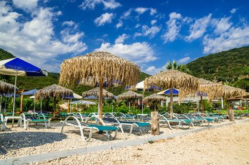 Antisamos beach Kefalonia island, Greece. Straw parasols (umbrellas) and sunbeds on a beautiful beach.