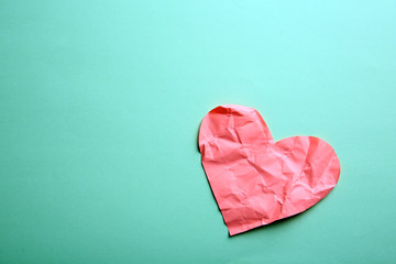 Crumpled paper heart on green background