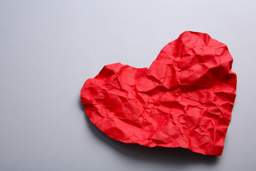 Crumpled paper heart on gray background