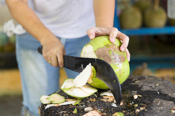 Woman cutting fresh coconut at the market