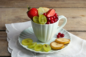 Cup of dessert with fresh fruits on wooden table, closeup