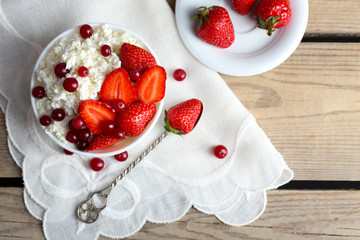 Bowl of cottage cheese with strawberry and cranberry on table, closeup