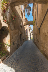 Fototapeta na wymiar Italian streets with arches on a sunny day and long shadows