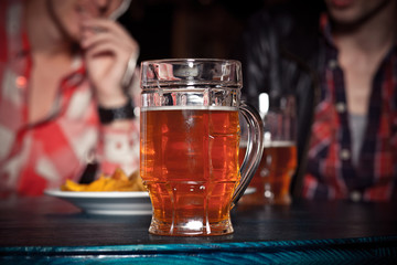 Glass of light beer on a dark pub.