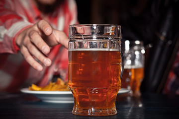 Glass of light beer on a dark pub.