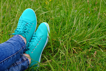 Female feet in gumshoes on green grass background