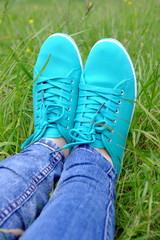 Female feet in gumshoes on green grass background